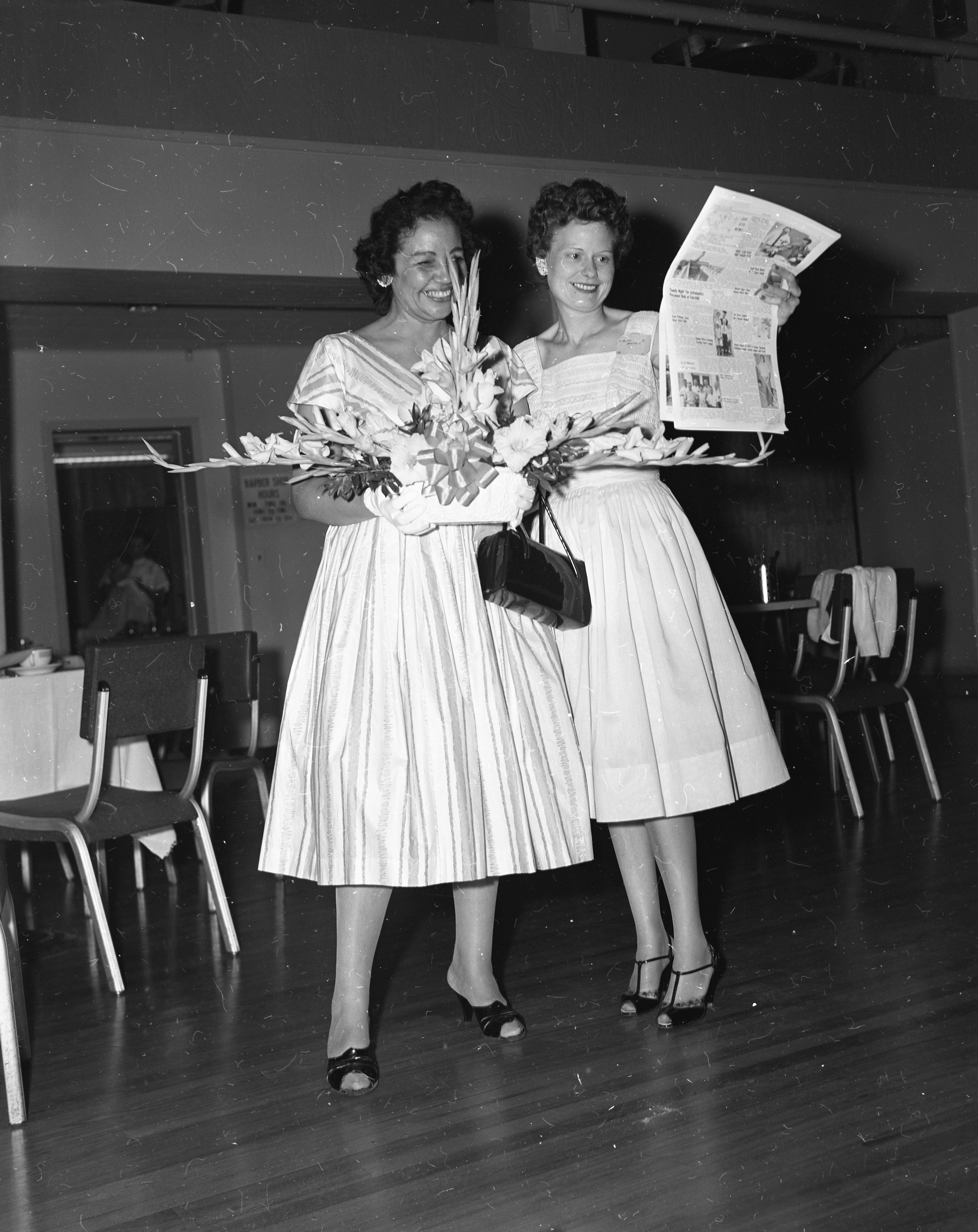 One woman holding gift while the other holds an issue of the Convairiety magazine. 