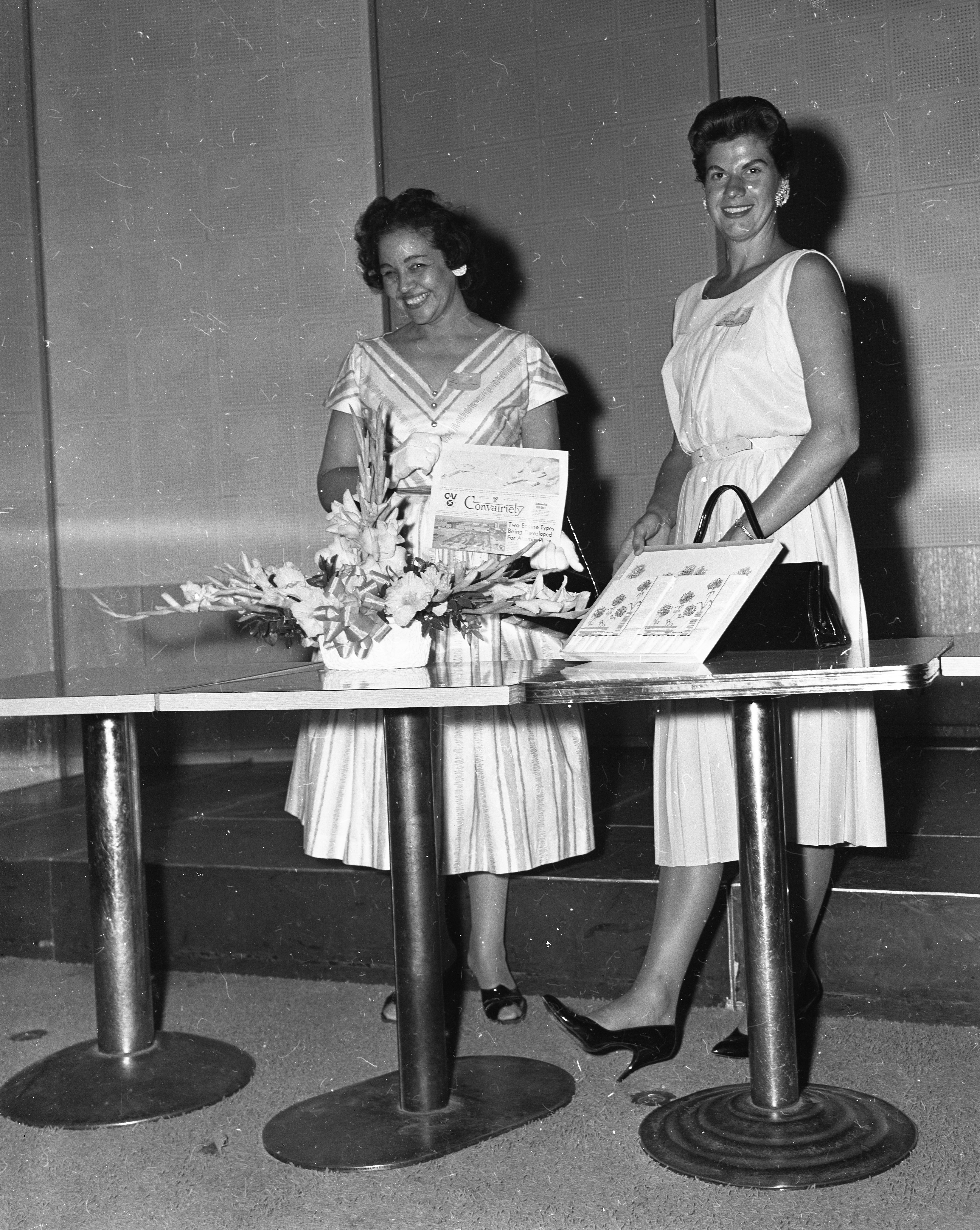 One woman holding gift while the other holds an issue of the Convairiety magazine.